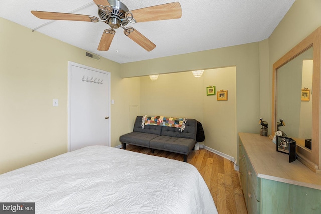 bedroom with a textured ceiling, wood-type flooring, and ceiling fan