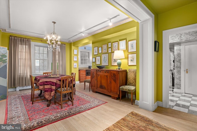 dining room with a notable chandelier, track lighting, and light wood-type flooring