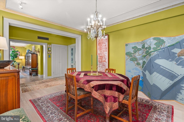 dining room with ornamental molding, a notable chandelier, and light hardwood / wood-style floors