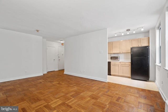 kitchen with light brown cabinets, light parquet flooring, and black fridge