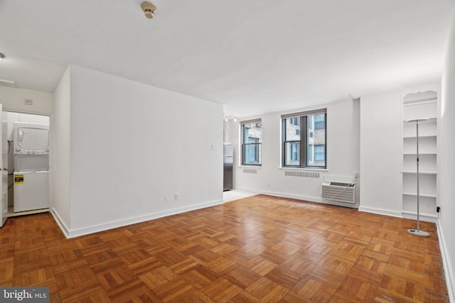 empty room with stacked washer / drying machine, parquet flooring, and an AC wall unit