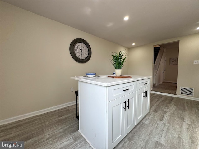 kitchen with white cabinetry, a center island, and light wood-type flooring