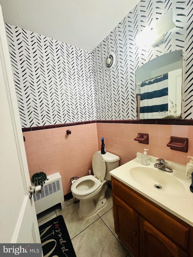 bathroom featuring toilet, tile walls, radiator heating unit, vanity, and tile patterned flooring