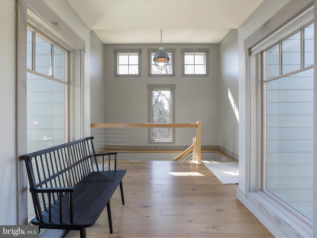 living area featuring a notable chandelier, wood finished floors, an upstairs landing, and baseboards