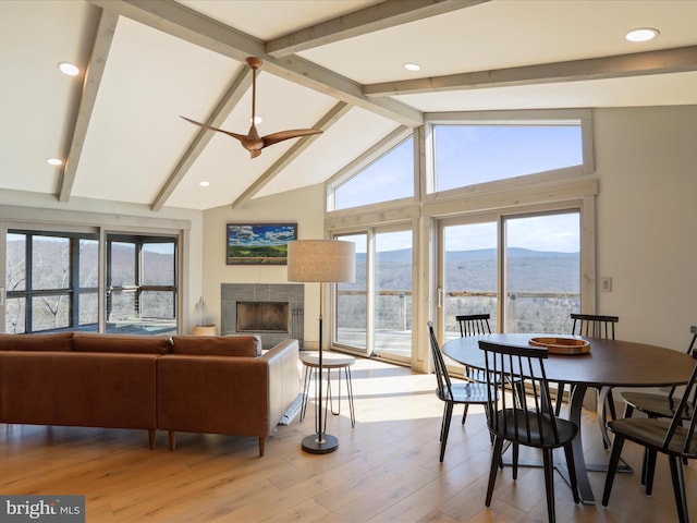 dining area with a ceiling fan, lofted ceiling with beams, wood finished floors, a fireplace, and a mountain view