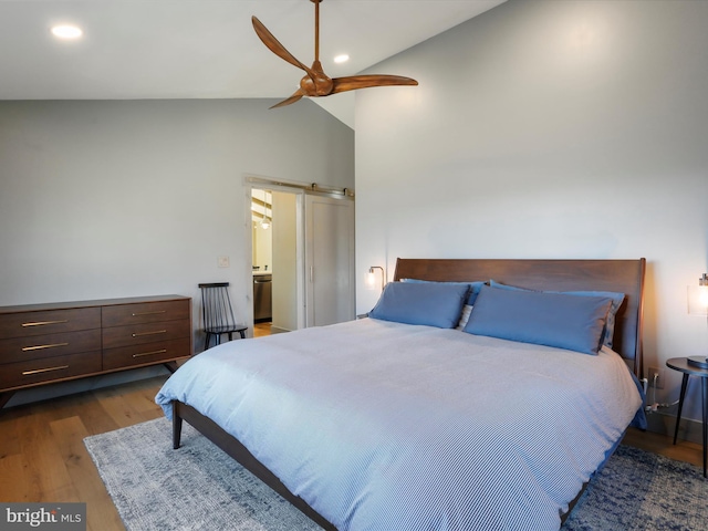 bedroom with a barn door, recessed lighting, wood finished floors, a ceiling fan, and vaulted ceiling