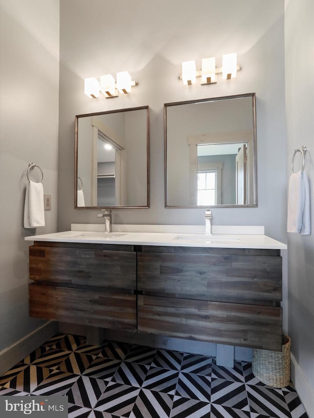 full bath featuring double vanity, a sink, and baseboards