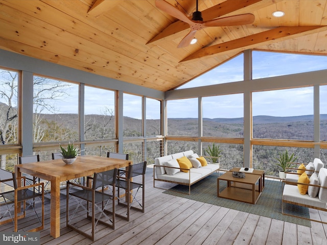 sunroom featuring vaulted ceiling with beams, wooden ceiling, a mountain view, and a wealth of natural light