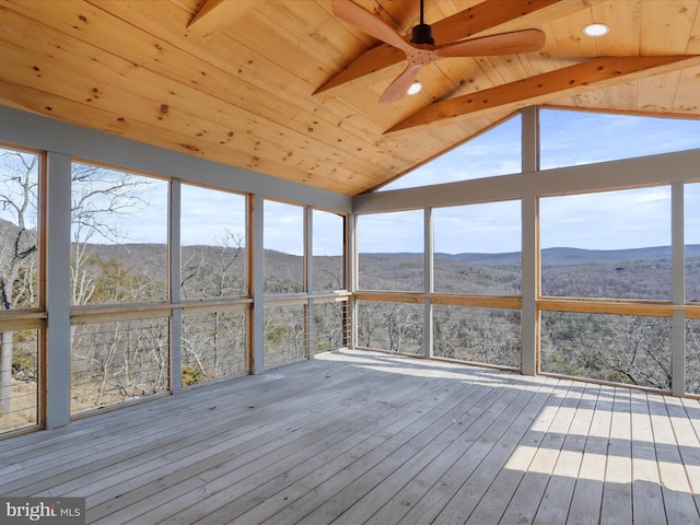 unfurnished sunroom with vaulted ceiling with beams, wooden ceiling, a mountain view, and ceiling fan