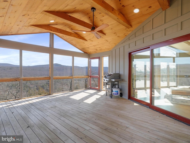 unfurnished sunroom with vaulted ceiling with beams, a wealth of natural light, and a mountain view