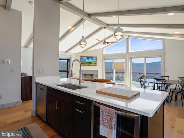 kitchen with a mountain view, beverage cooler, a sink, light wood-style floors, and dishwasher