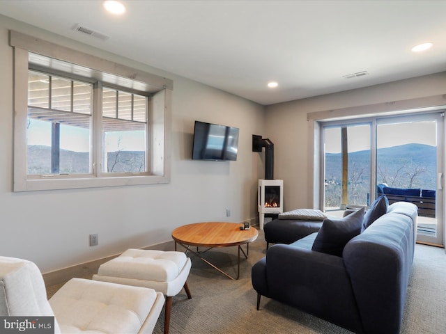 carpeted living room featuring a wood stove, baseboards, visible vents, and recessed lighting