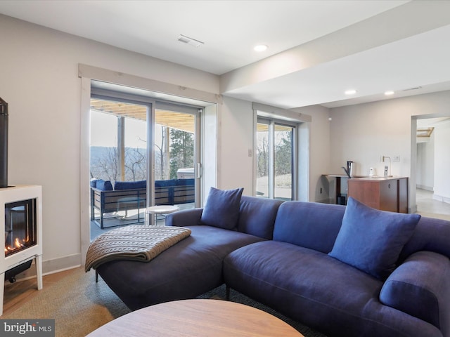 living area featuring recessed lighting, plenty of natural light, visible vents, and baseboards