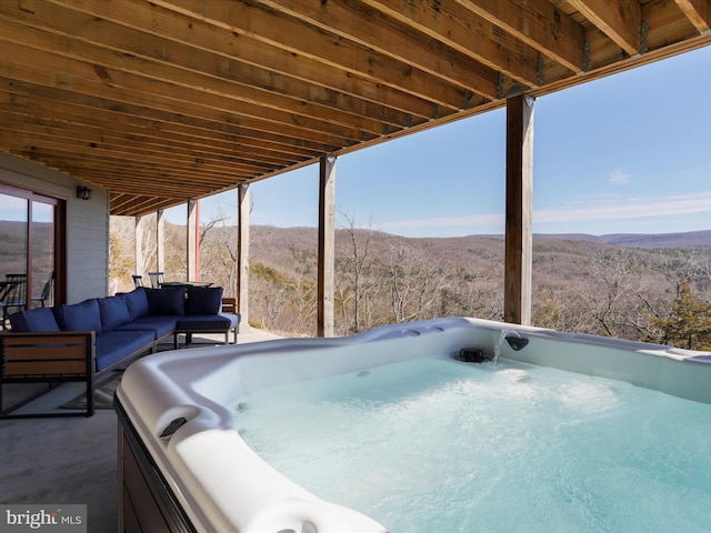 view of patio with an outdoor hangout area, a wooded view, a mountain view, and a hot tub