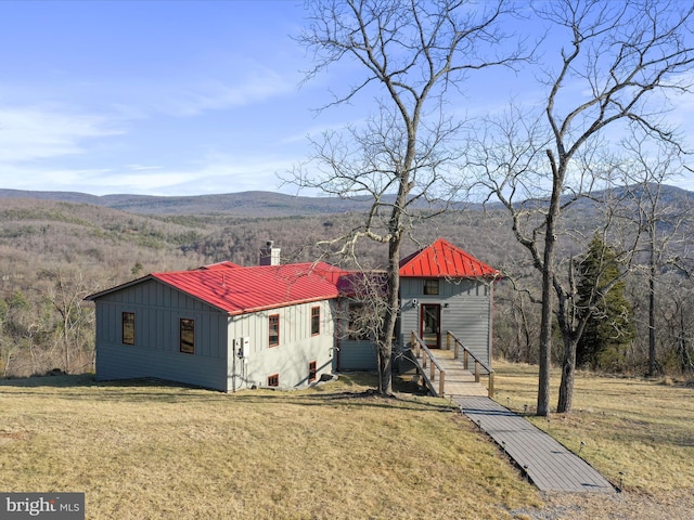 view of front of property featuring metal roof, board and batten siding, a front yard, and a mountain view