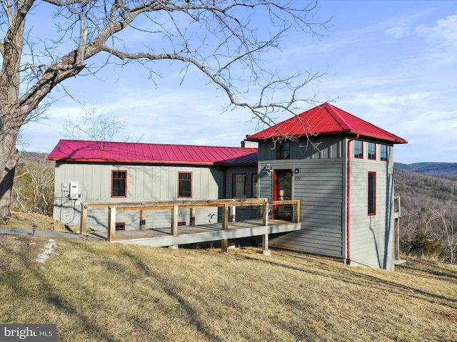 exterior space with board and batten siding, metal roof, a garage, and a lawn