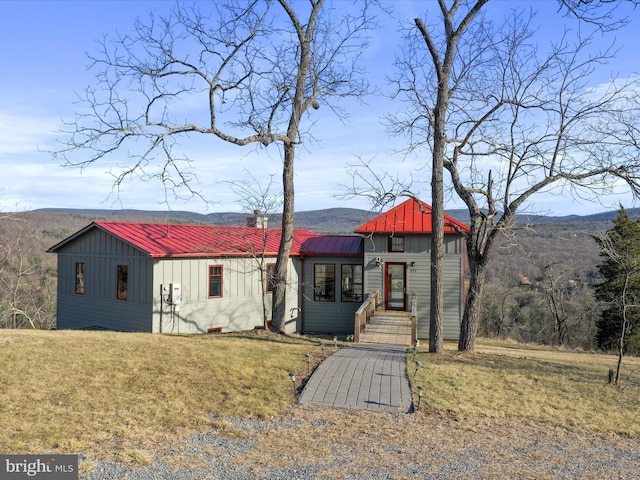 view of front facade with a mountain view, metal roof, board and batten siding, and a front yard