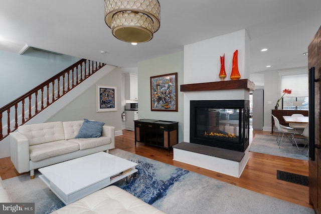 living area with recessed lighting, visible vents, stairway, and wood finished floors