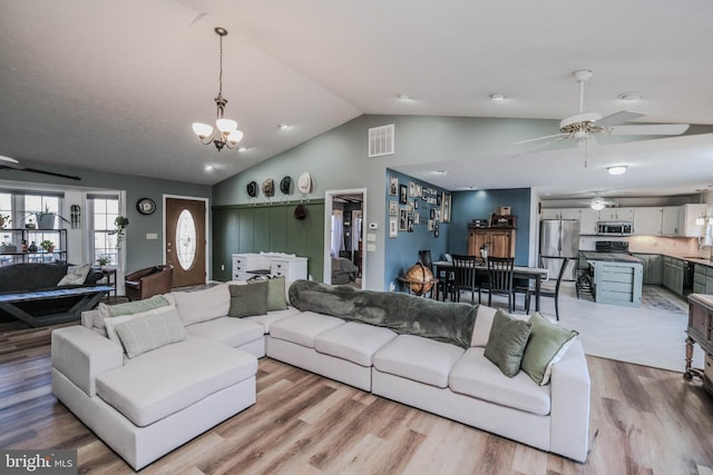 living room featuring ceiling fan with notable chandelier, vaulted ceiling, and light hardwood / wood-style flooring