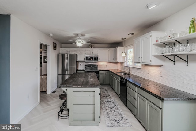 kitchen with sink, gray cabinets, a center island, tasteful backsplash, and black appliances