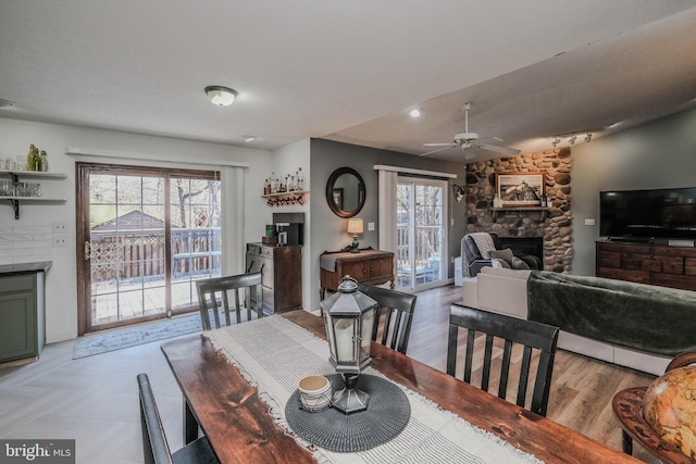 dining space featuring lofted ceiling, a fireplace, ceiling fan, and light wood-type flooring