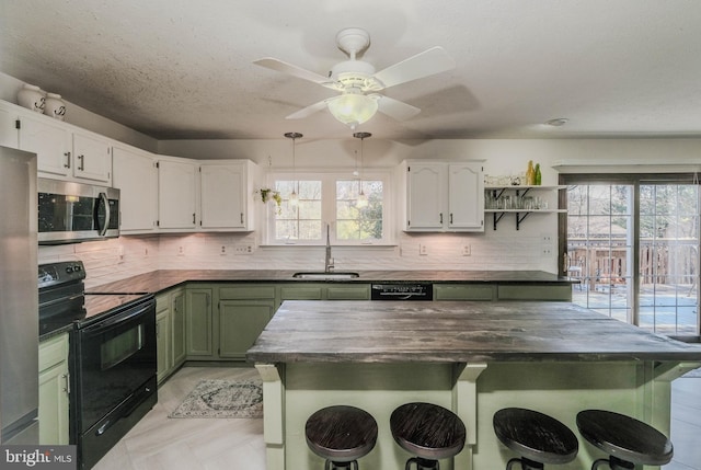 kitchen with sink, black appliances, a breakfast bar, and green cabinetry