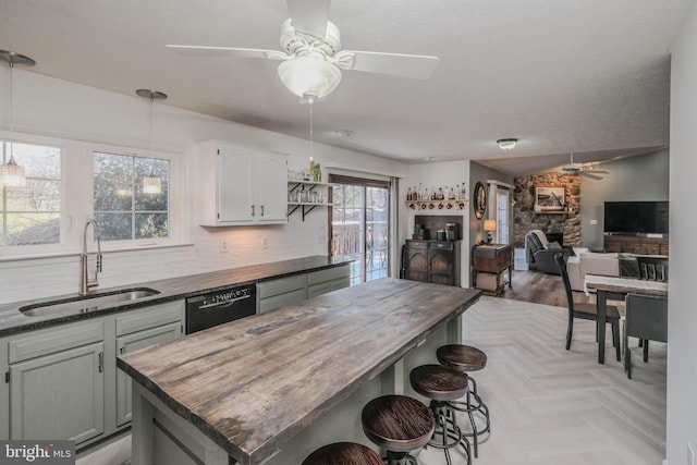 kitchen featuring a breakfast bar, black dishwasher, sink, decorative backsplash, and ceiling fan