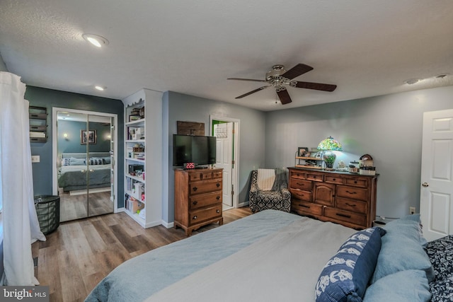 bedroom with ceiling fan, light hardwood / wood-style floors, a closet, and a textured ceiling