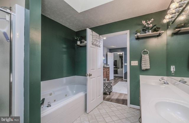 bathroom featuring vanity, tiled bath, tile patterned floors, and a textured ceiling