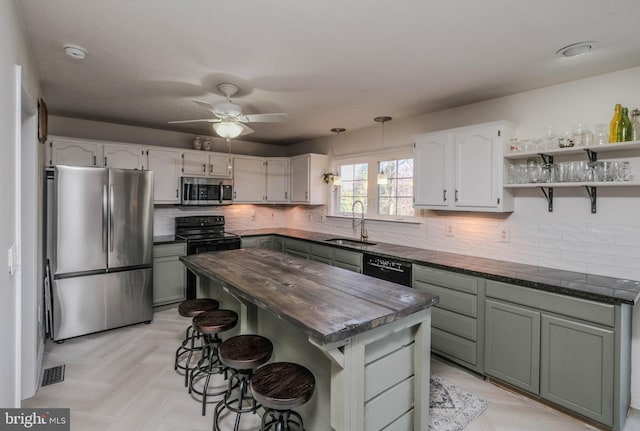 kitchen featuring sink, backsplash, a kitchen breakfast bar, a center island, and black appliances