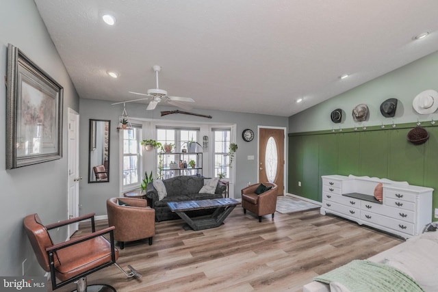 living room with vaulted ceiling, ceiling fan, and light wood-type flooring