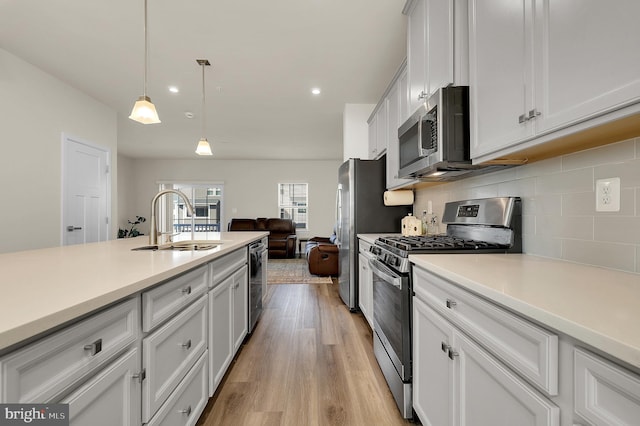 kitchen with appliances with stainless steel finishes, decorative light fixtures, white cabinetry, sink, and decorative backsplash