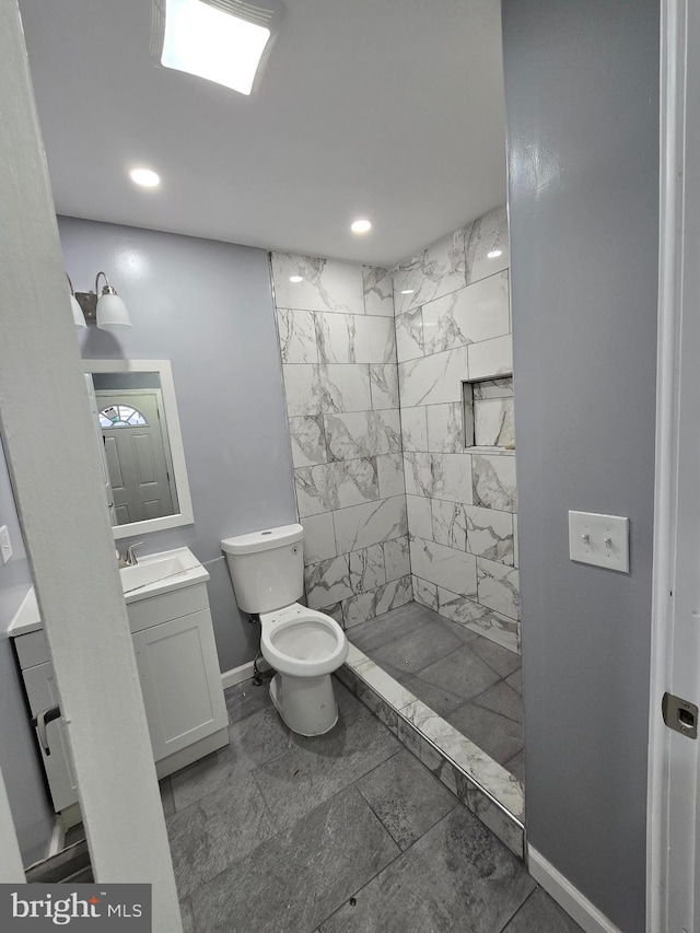 bathroom with vanity, toilet, and a tile shower