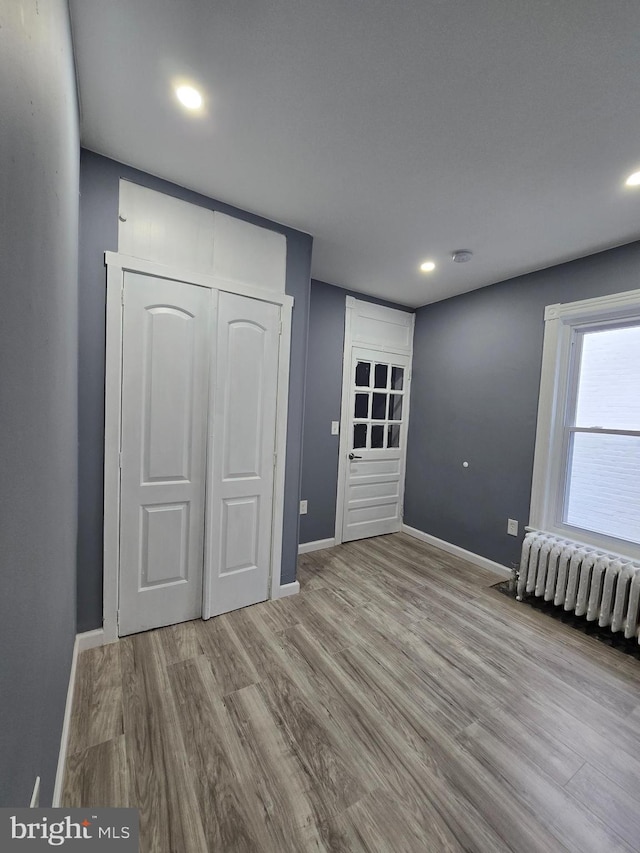 unfurnished bedroom with a closet, radiator, and light hardwood / wood-style flooring