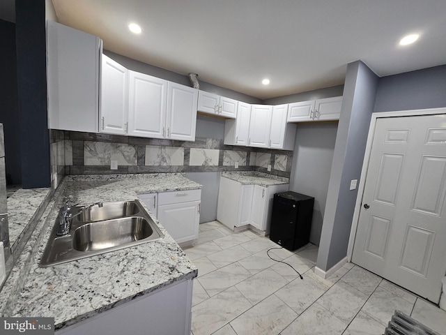 kitchen with light stone countertops, sink, decorative backsplash, and white cabinets