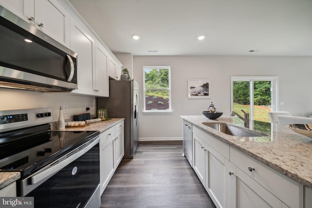 kitchen with appliances with stainless steel finishes, sink, white cabinets, and light stone counters