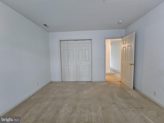 unfurnished bedroom with light colored carpet and a closet