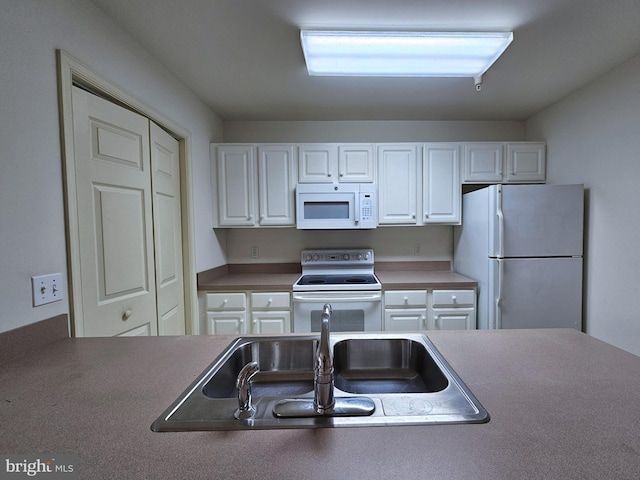 kitchen featuring sink, white cabinets, and white appliances