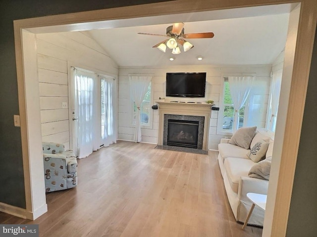 living room with hardwood / wood-style flooring, lofted ceiling, a healthy amount of sunlight, and a high end fireplace