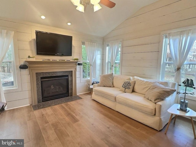 living room with wood-type flooring, vaulted ceiling, and wooden walls