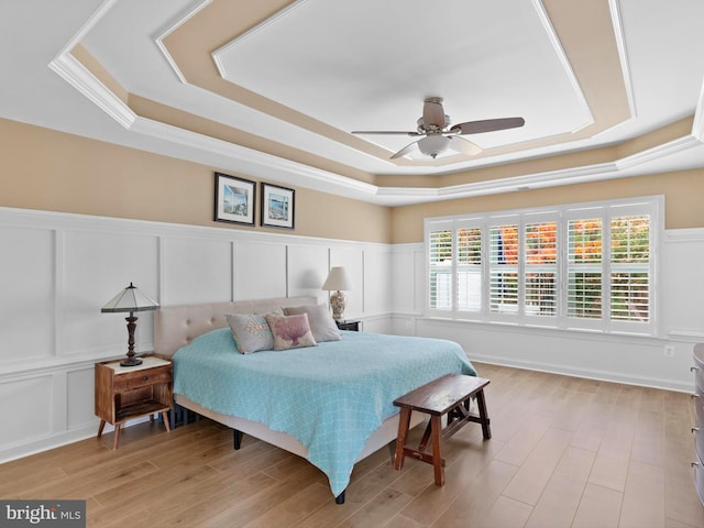 bedroom featuring light hardwood / wood-style floors, a raised ceiling, and ceiling fan