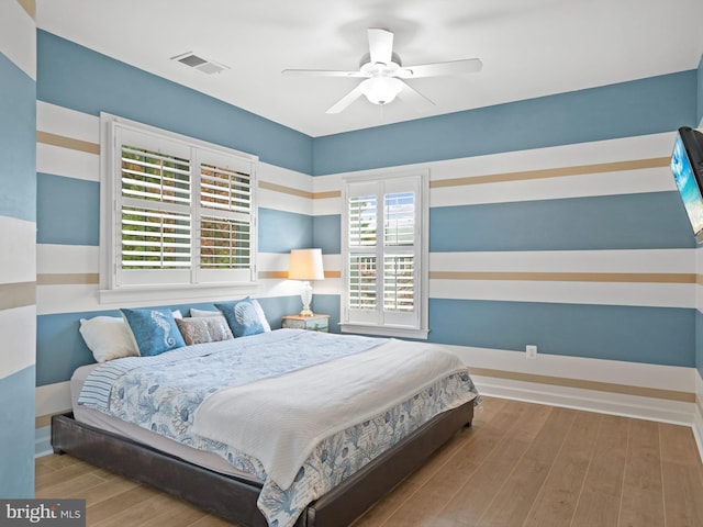 bedroom with multiple windows, hardwood / wood-style floors, and ceiling fan