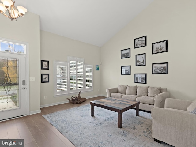 living room with an inviting chandelier, high vaulted ceiling, and light hardwood / wood-style floors