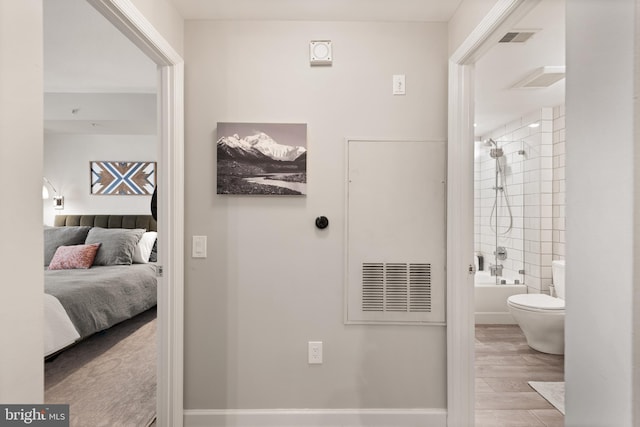 bathroom with tiled shower / bath combo, hardwood / wood-style floors, and toilet