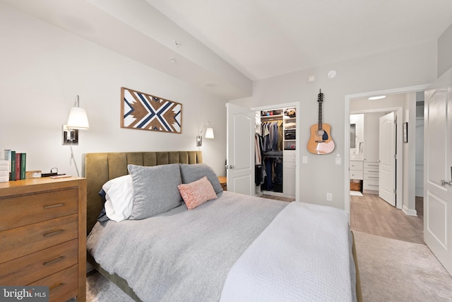 bedroom featuring a walk in closet, connected bathroom, light hardwood / wood-style floors, and a closet