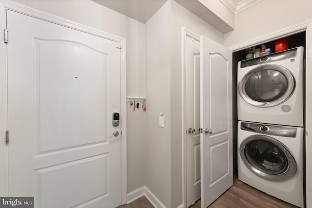 clothes washing area with hardwood / wood-style floors and stacked washer / dryer