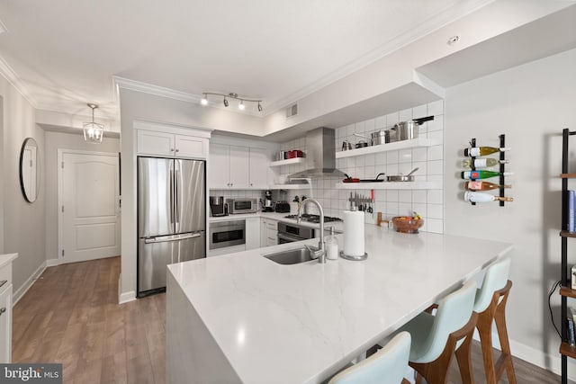 kitchen featuring pendant lighting, stainless steel appliances, extractor fan, white cabinets, and kitchen peninsula