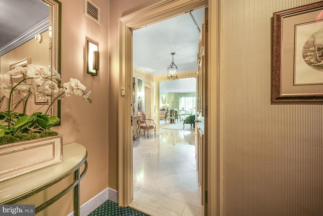 corridor with baseboards, visible vents, and a chandelier