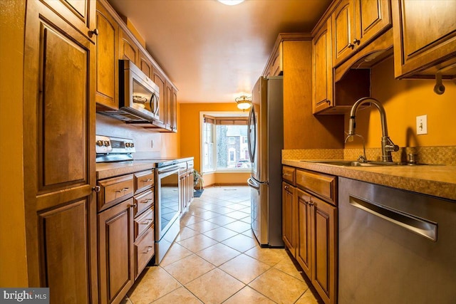 kitchen with stainless steel appliances, light tile patterned flooring, and sink