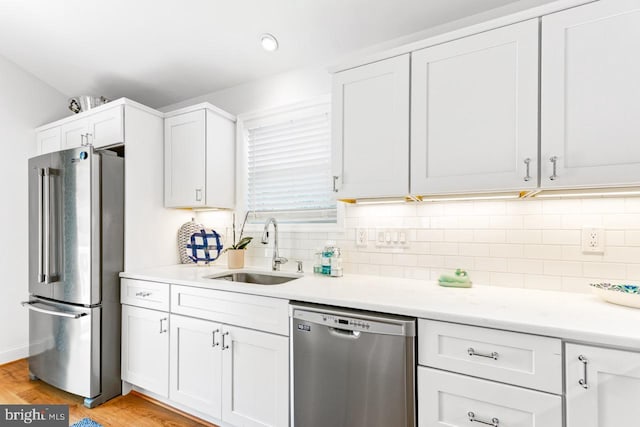 kitchen with tasteful backsplash, white cabinetry, appliances with stainless steel finishes, and sink